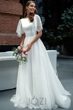 a woman in a white wedding dress posing for the camera with her bouquet and veil over her head