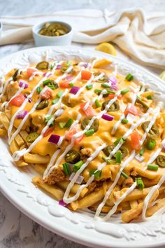 a white plate topped with cheesy fries covered in cheese and toppings on top of it