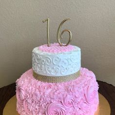 a pink and white cake with gold numbers on the top is sitting on a table