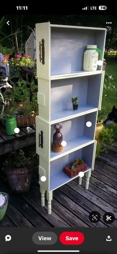 a white bookcase sitting on top of a wooden deck next to potted plants