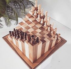 a wooden chess set on top of a table next to a potted palm tree