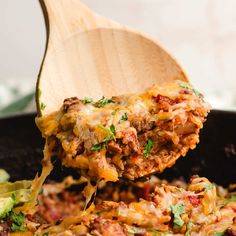 a wooden spoon scooping some food out of a skillet