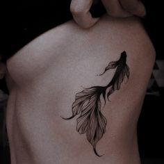 a woman's back with a tattoo on her stomach and an image of a feather