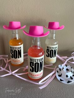 three bottles with pink hats on them sitting next to a white and black polka dot hat