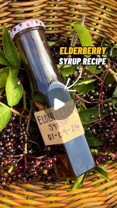 a bottle of elderberry syrup sitting in a basket with berries and leaves around it