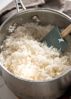 rice being cooked in a pot with a wooden spoon