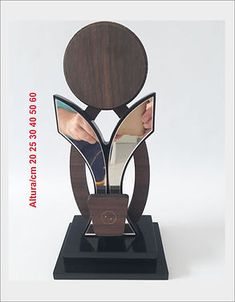 a wooden and metal sculpture with a mirror in it's center on a black base