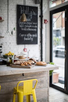 bread and pastries are sitting on the counter in front of a chalkboard sign