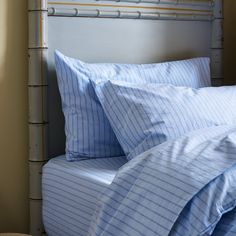 a bed with blue and white striped sheets, pillows and pillow cases on top of it