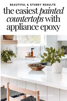 a white counter top sitting under a window next to a bowl filled with green plants