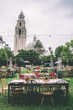 an outdoor dining area with tables and chairs in front of a large church steeple