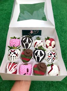 a box filled with lots of chocolate covered strawberries on top of a green field