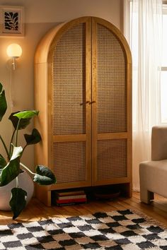 a living room with a large wooden cabinet next to a couch and potted plant