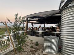 people are standing on the top of a building with metal tanks in front of them