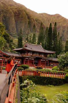 a woman standing in front of a building with mountains in the backgrouds