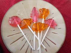 four lollipops on a white plate with pink and orange candies in them