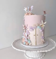 there is a pink and white cake with flowers on the top, sitting on a platter