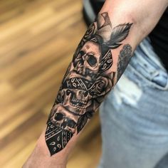 a man's arm with a skull and roses tattoo on the left side of his arm