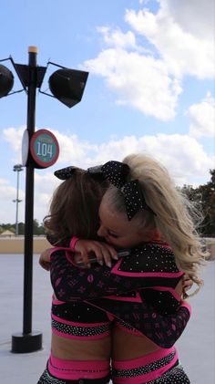 two women hugging each other in front of a street light