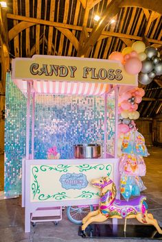 there is a candy floss stand with balloons on the top and an ice cream cart behind it