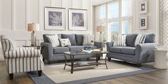 a living room filled with blue furniture and striped pillows on top of a wooden floor