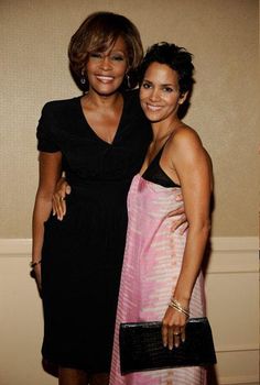 two women standing next to each other in front of a wall