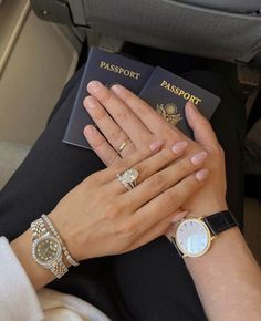 two people holding their hands together while sitting in an airplane with passport and watch on their wrist