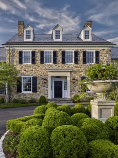 a large stone house with black shutters and white trim on the windows is shown