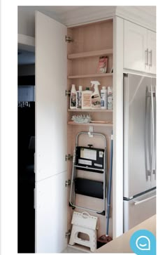 a kitchen with white cabinets and stainless steel refrigerator freezer combo in the corner, next to an open pantry door