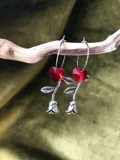 "These romantic gothic silver rose and red crystal heart dangle and drop hoop earrings would make the perfect cottagecore jewellery Valentine's gift or love token for any time of the year! In Roman Mythology, it was reported and observed that wealthy Romans prefer the flowers of red Roses to associate beauty and love. The goddesses love to pamper their body with a bath filled with Roses while some of them filled their bedchambers and bedrooms with flowers and petals of red Roses because of the pleasant smell and for soft skin. The heart and rose together typically represents love, passion, and desire and the red rose particularly was initially tied to Aphrodite who was said to have run across a field, pricking her ankles as she rushed to her dying lovers side.  Myth reveals that she is res Cottagecore Jewellery, Gothic Cottagecore, Cottagecore Wedding, Cottagecore Jewelry, Romantic Earrings, Gothic Earrings, Dark Cottagecore, Love Token, Valentine's Gift