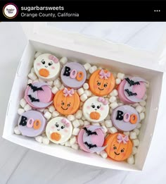 a box filled with lots of decorated cookies in the shape of pumpkins and bats