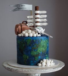 a blue cake with white candies and an arrow on top that says travel the world