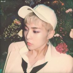 a young man wearing a white sailor's hat and black tie with flowers in the background