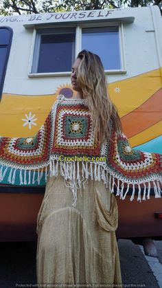 a woman standing in front of a trailer with a crocheted blanket on it