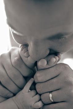 a close up of a person holding a baby's hand and touching it with their fingers