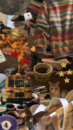 a collage of books, cups, and other items on a table with a cat sitting in the middle