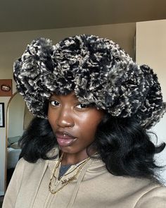 a woman wearing a black and white hat with large curls on it's head