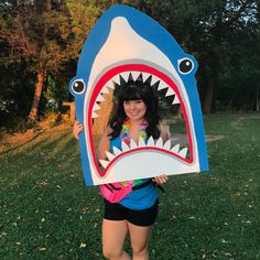 a woman is holding up a cardboard shark