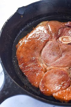 some meat is cooking in a black skillet on the stove top and it looks like they have been cooked