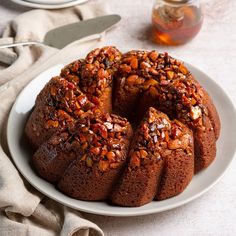 a bundt cake on a white plate next to a jar of honey