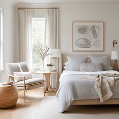 a bedroom with a bed, chair and table in front of two windows next to each other