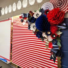 a bulletin board is decorated with red, white and blue paper flowers on it's side