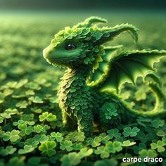 a green dragon sitting on top of clover covered ground