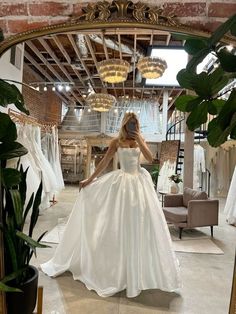 a woman standing in front of a mirror wearing a wedding dress