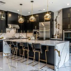 a large kitchen with marble counter tops and gold accents on the cabinets, along with bar stools