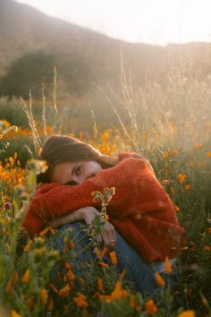 a woman is sitting in the middle of a field with yellow flowers and she has her arms around her neck