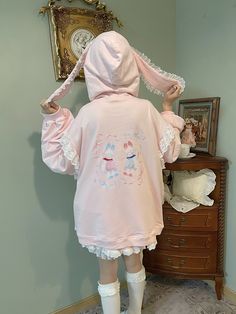 This hoodie is crafted from 100% cotton and features a loose fit, ensuring maximum comfort and coziness. The back of the printed version showcases an adorable bunny print, adding a touch of playful charm. The hoodie is designed with rabbit ear accents and delicate lace trim, enhancing its overall elegance. The sleeves and pocket edges are also adorned with lace details, creating a cohesive and stylish look. The side pockets are designed with a semi-closure to prevent items from falling out easil Spring Cartoon Print Hoodie Top, Cute Long Sleeve Hoodie For Loungewear, Casual Cartoon Print Hoodie For Spring, Casual Spring Hoodie With Cartoon Print, Cotton Kawaii Hoodie With Cartoon Print, Kawaii Winter Hoodie For Loungewear, Kawaii Cotton Hoodie With Cartoon Print, Spring Cartoon Print Hoodie Sweatshirt, Cotton Hoodie With Cartoon Print For Loungewear