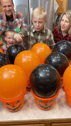 a group of people that are standing in front of some orange and black balls on a table