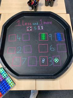 a blackboard with colored numbers and dices on it next to some toy blocks