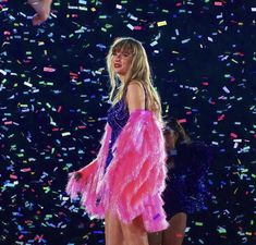 a woman in a pink feathered dress on stage with confetti around her